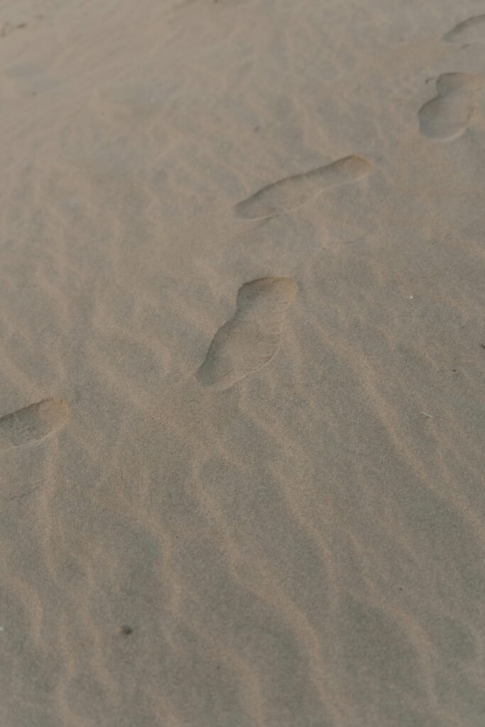 Close-up view of human footprints on a sandy desert surface with a natural texture.